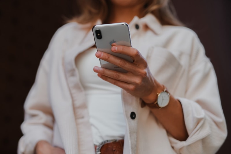 woman holding iphone watch accessories white outfit