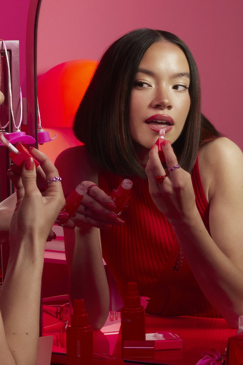 woman applying lip gloss in a red room, tinder and e.l.f. cosmetics collab, makeup, beauty