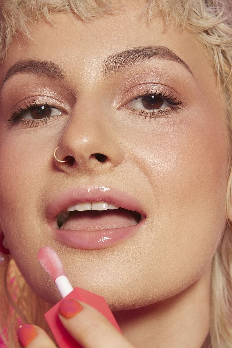 woman applying lip gloss in a red room, tinder and e.l.f. cosmetics collab, makeup, beauty