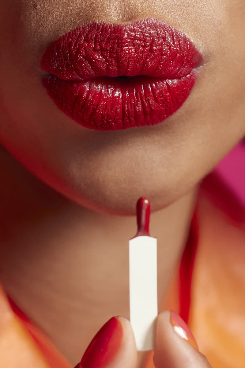 woman applying lip gloss in a red room, tinder and e.l.f. cosmetics collab, makeup, beauty
