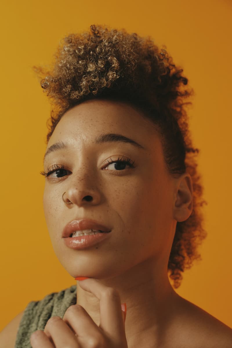 woman with bantu knots poses with pattern beauty haircare products, hair steamer, tracee ellis ross