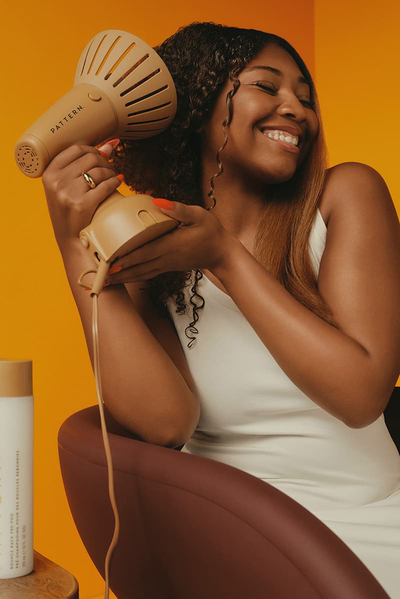 woman with bantu knots poses with pattern beauty haircare products, hair steamer, tracee ellis ross