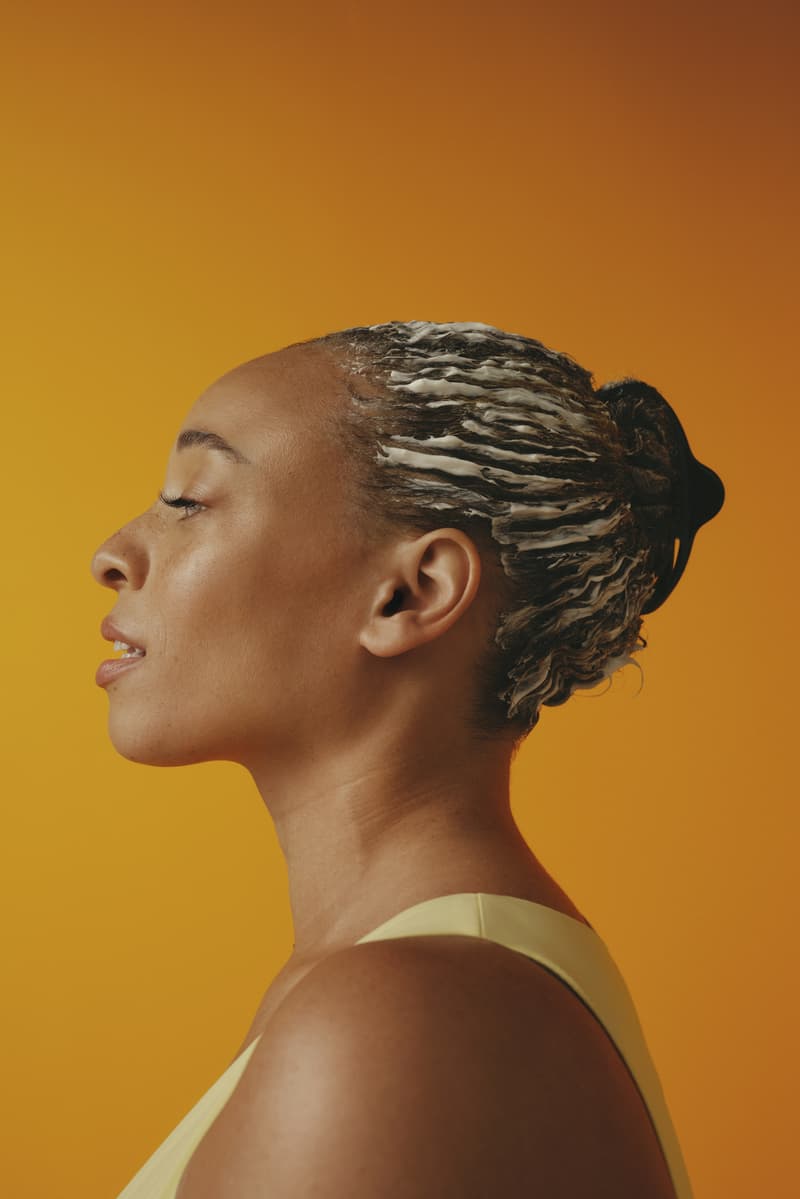 woman with bantu knots poses with pattern beauty haircare products, hair steamer, tracee ellis ross