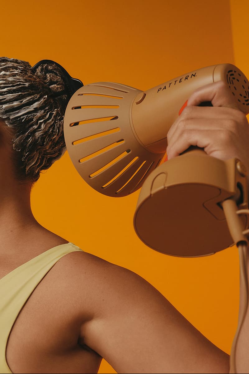 woman with bantu knots poses with pattern beauty haircare products, hair steamer, tracee ellis ross