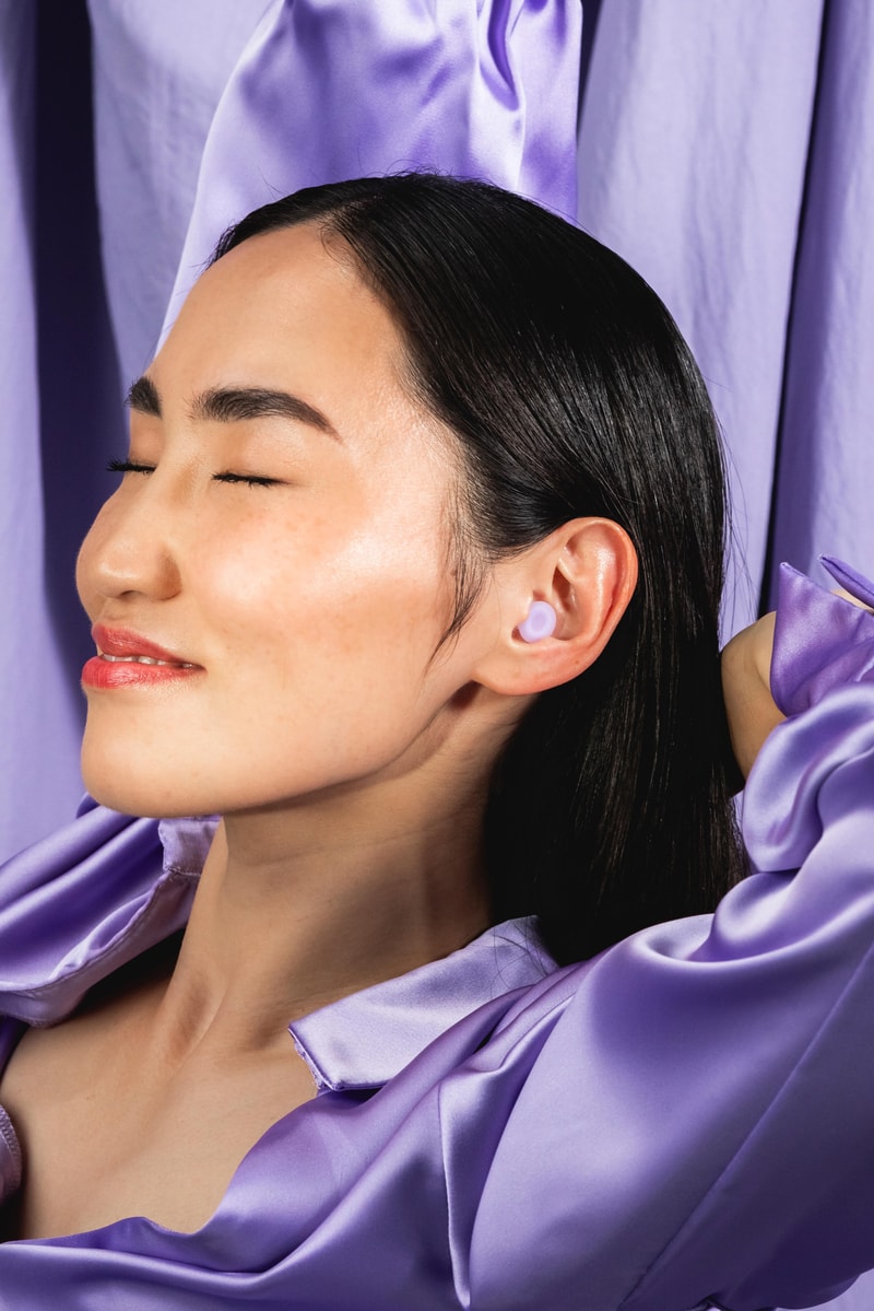 person sleeping inside of grey blankets with loops sleep ear plugs on, beauty