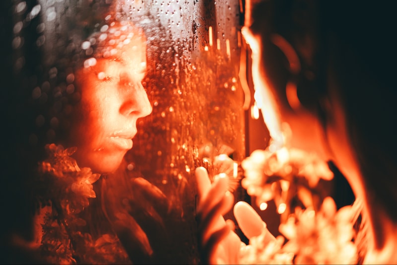 woman looking at her reflection with sakura flowers in red light, pheromone perfume, do they actually work