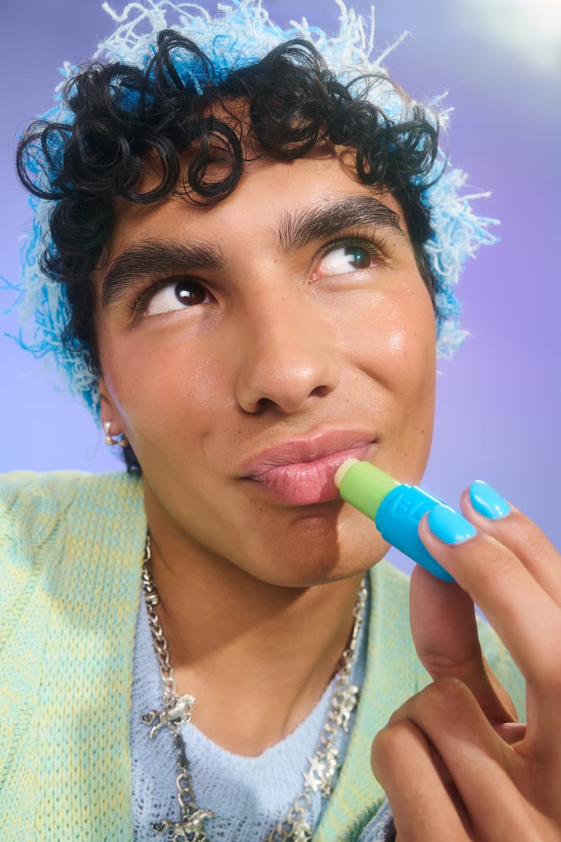 woman with bright blue eyeshadow and ear muffs applying bubble skincare new mint lip balm, beauty, gen-z