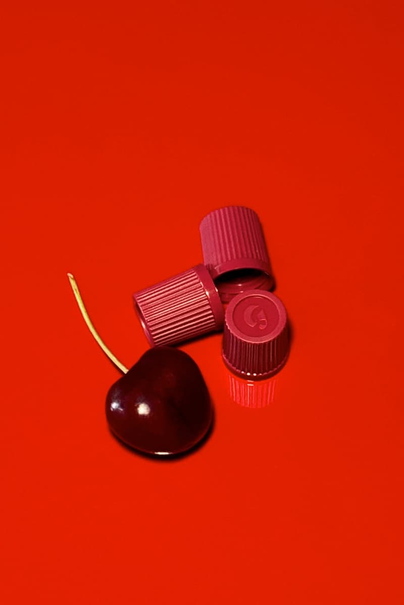 woman posing on top of a convertible with glossier balm dot com in her hand, black cherry collection, makeup, skincare
