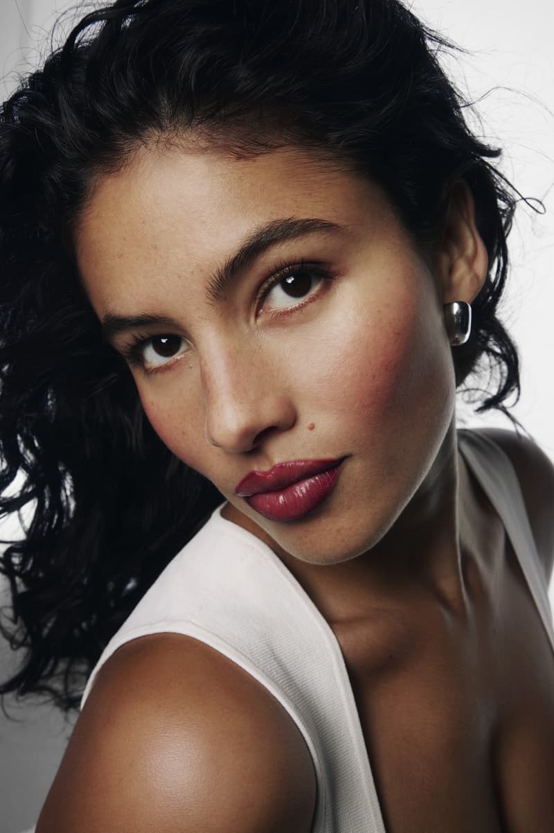 woman posing on top of a convertible with glossier balm dot com in her hand, black cherry collection, makeup, skincare
