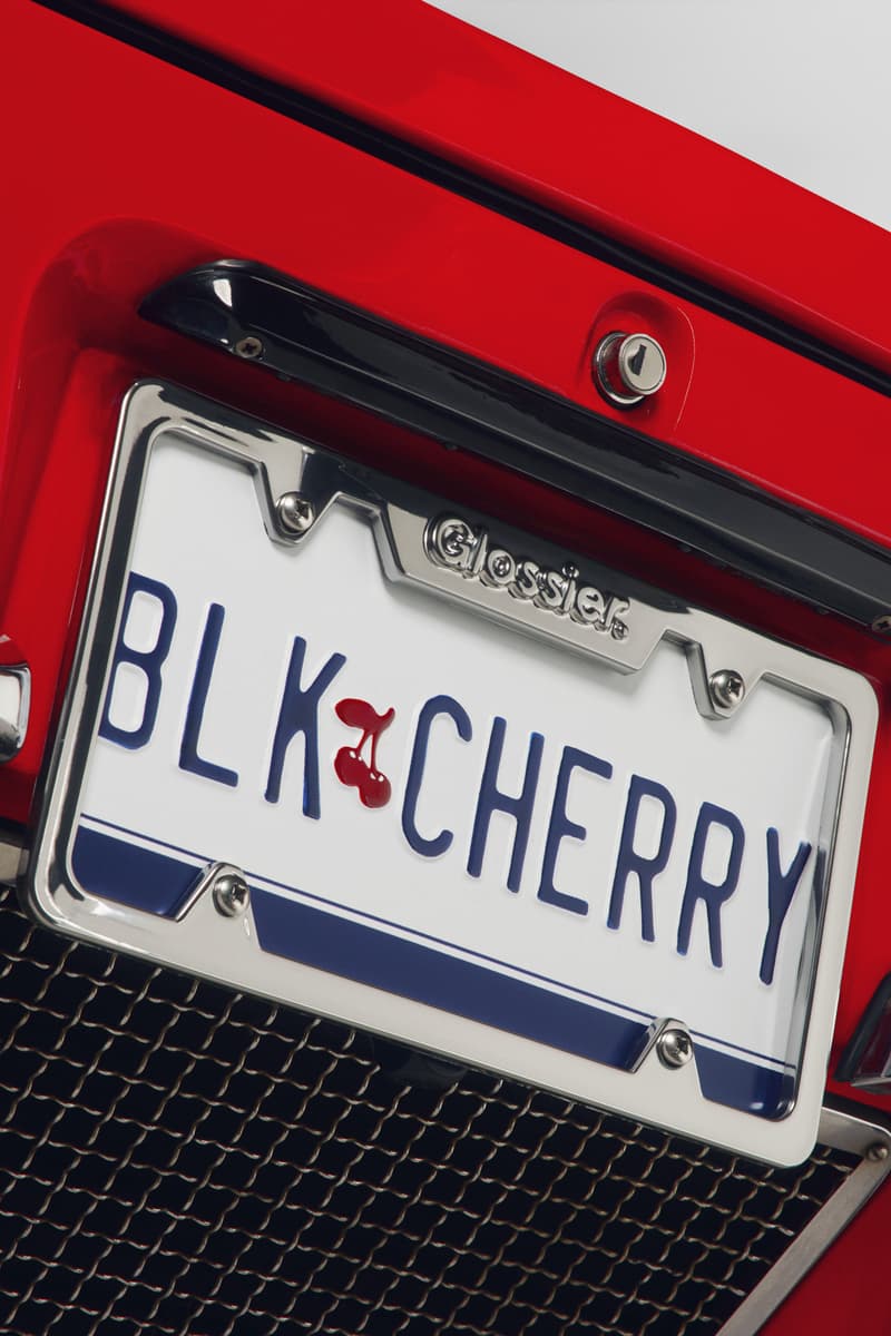 woman posing on top of a convertible with glossier balm dot com in her hand, black cherry collection, makeup, skincare