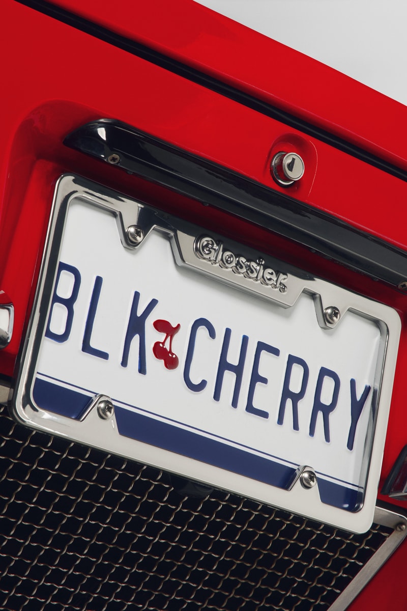 woman posing on top of a convertible with glossier balm dot com in her hand, black cherry collection, makeup, skincare