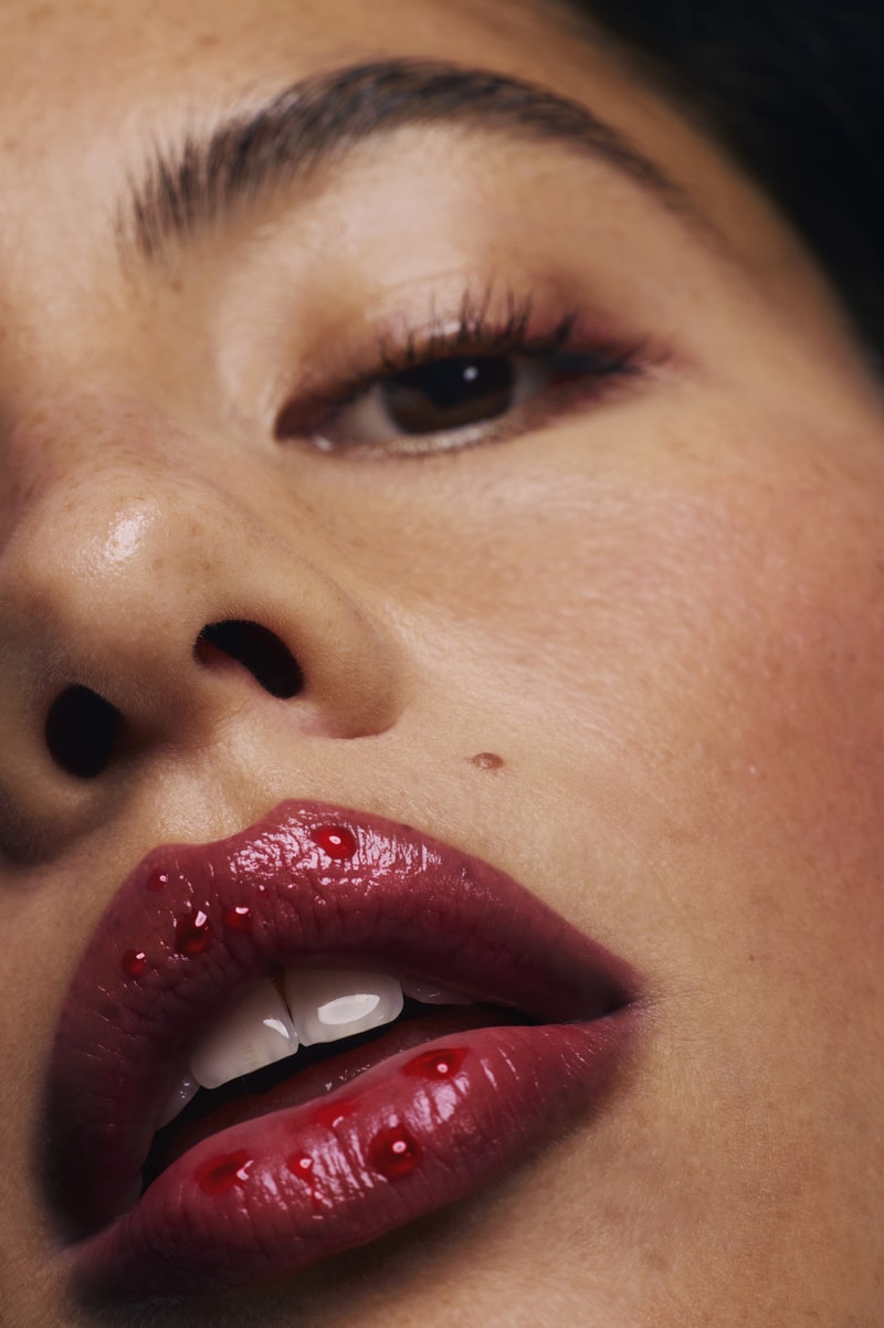 woman posing on top of a convertible with glossier balm dot com in her hand, black cherry collection, makeup, skincare