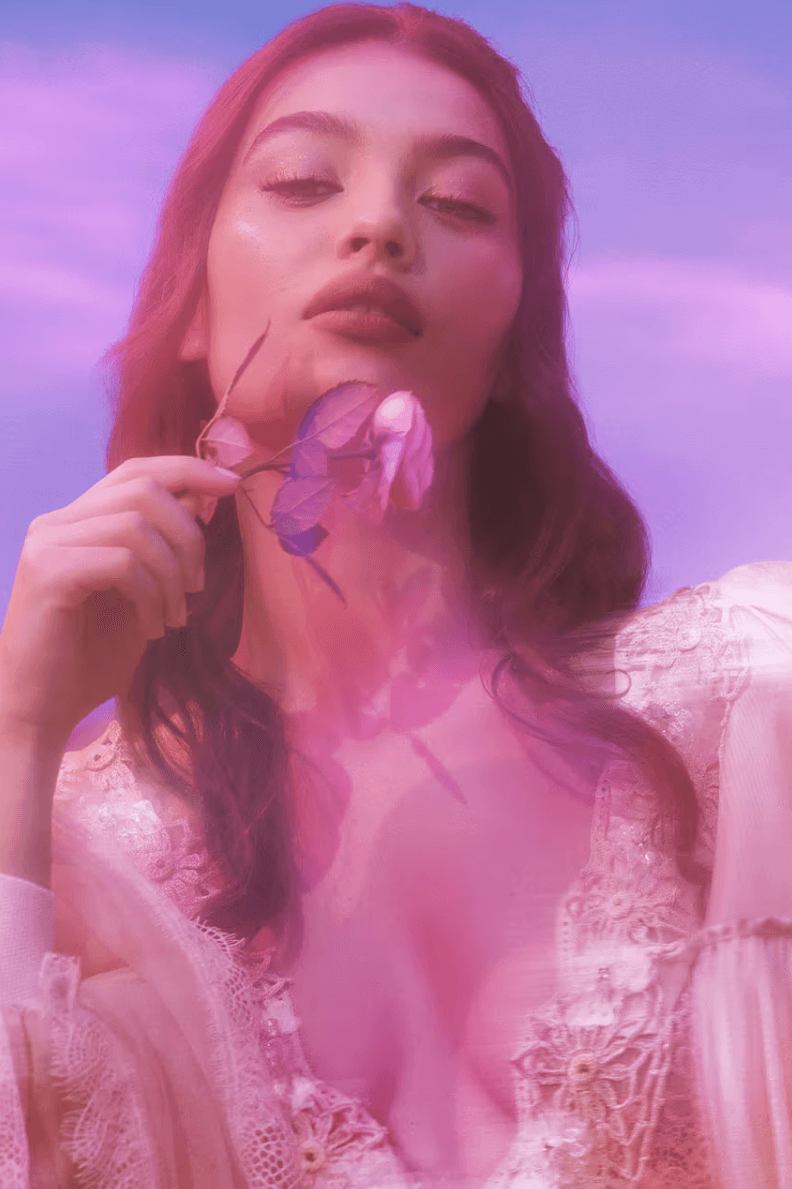 woman in purple and pink light posing with flower, makeup predictions 2025, castlecore, goddesscore, matte skin, dewy skin, grunge, beauty 
