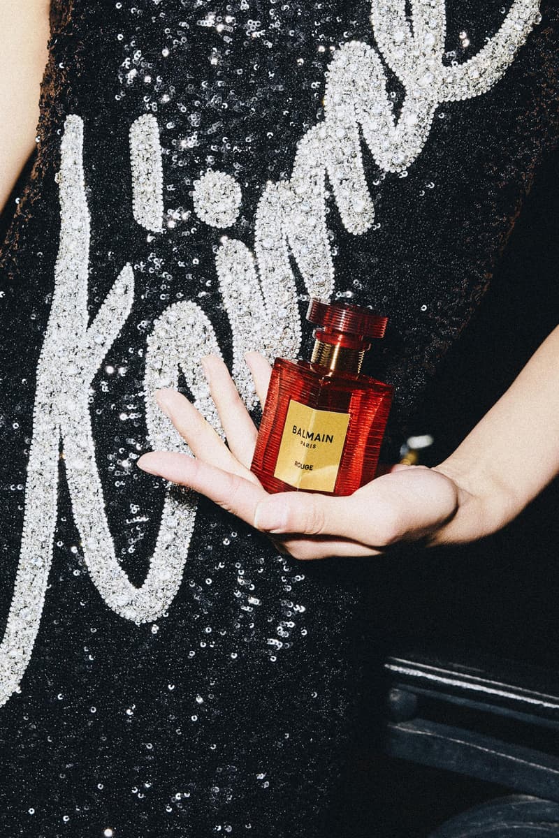 two woman posing across from each other with big gold earrings and red lipstick, new rouge perfume from balmain beauty, fragrance