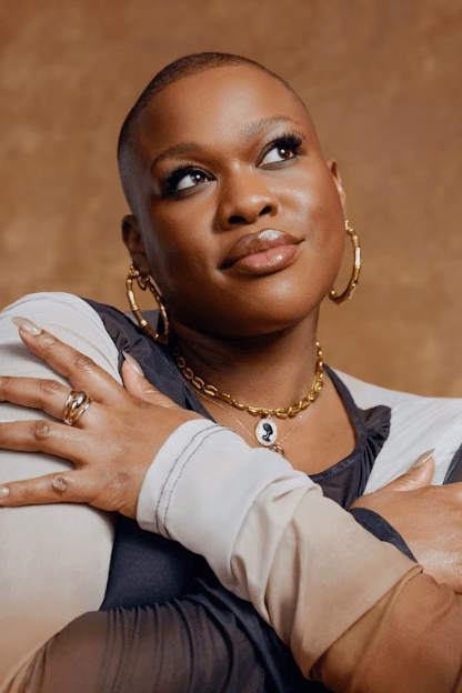 woman with braided knots on top of her head posing in orange dress, i see you, rare beauty makeup campaign