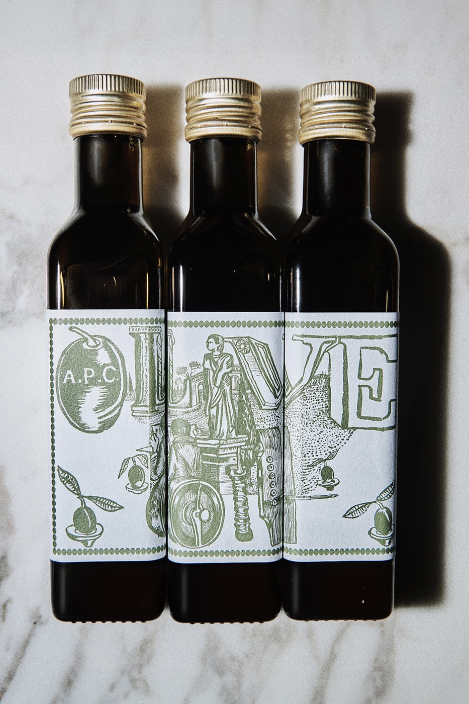 A.P.C. Drops Cooking Essentials in Olive Oil and Apron Combo france season 3 kitchen mathias m/m graphic studio