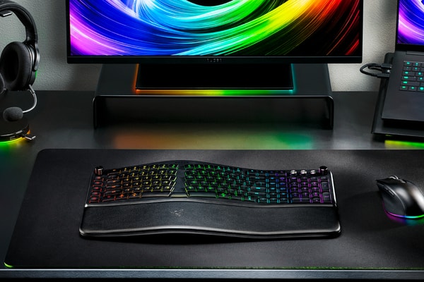 Razer Pro Type Ergo wireless ergonomic keyboard with split Alice-style layout, wrist rest and RGB lighting on a modern desk setup.