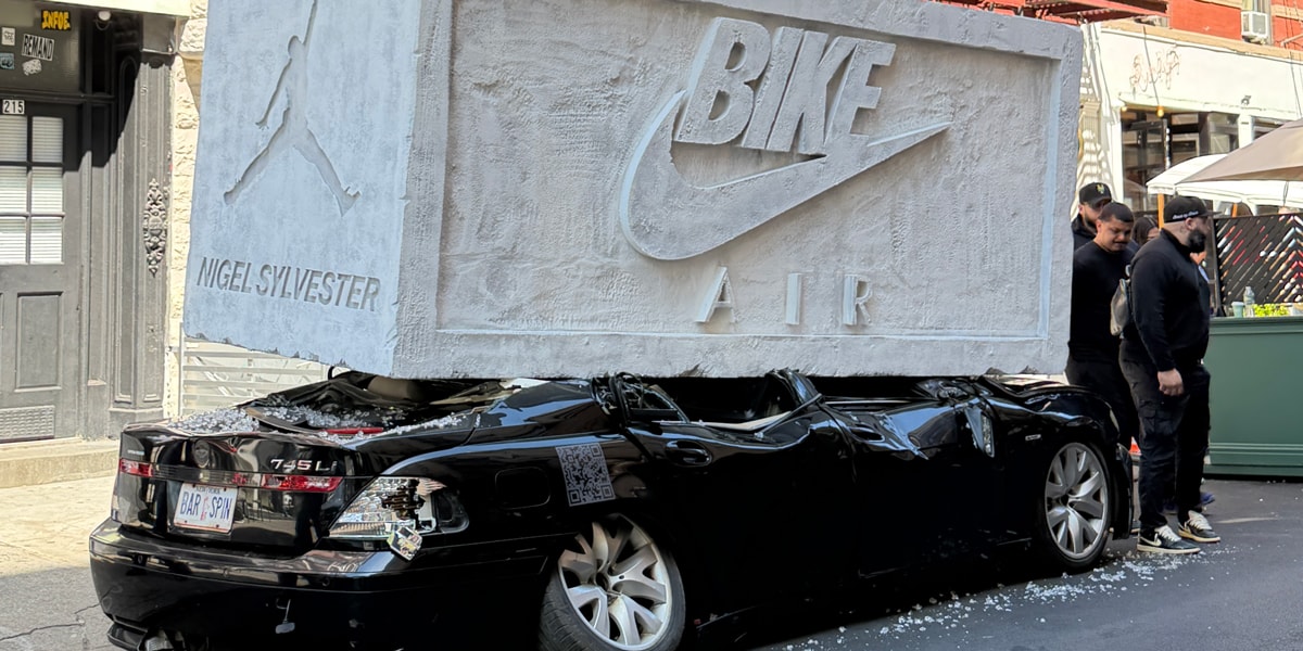 The Weight of Progress installation: a giant brick crushing a BMW on Mulberry Street, NYC