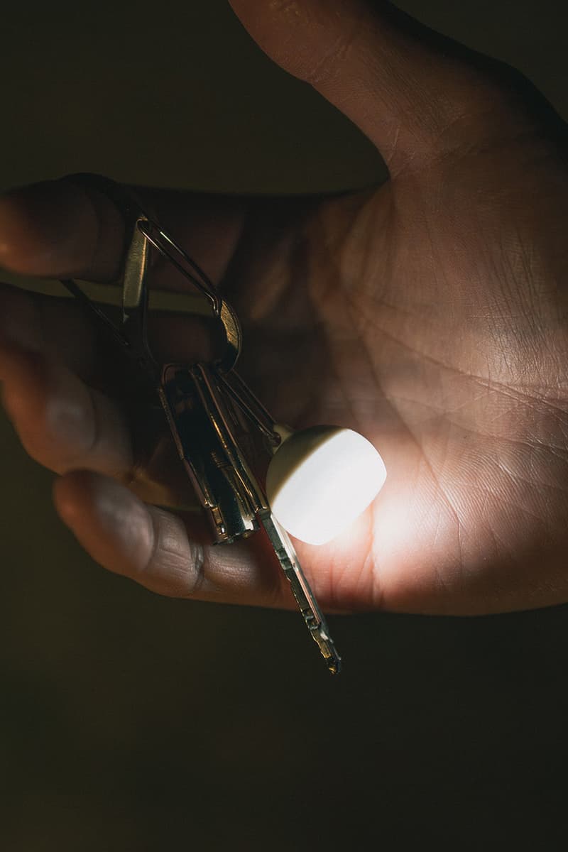 Snow Peak Micro Hozuki mini lantern clipped to a backpack strap, showing compact waterproof LED design