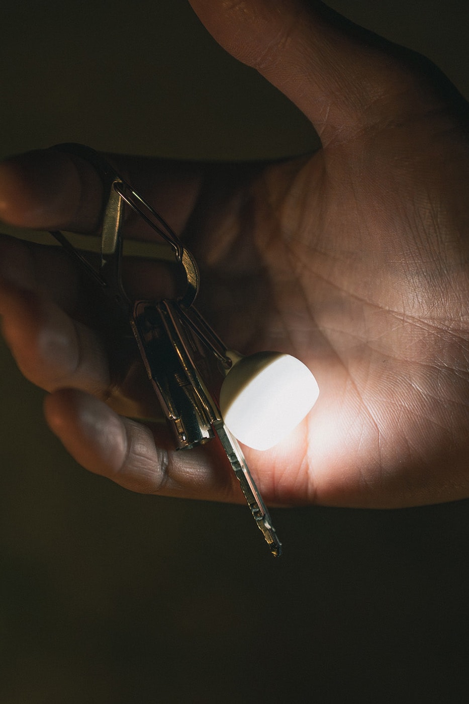 Snow Peak Micro Hozuki mini lantern clipped to a backpack strap, showing compact waterproof LED design