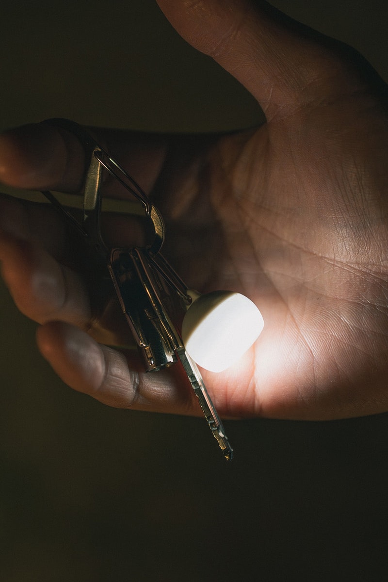 Snow Peak Micro Hozuki mini lantern clipped to a backpack strap, showing compact waterproof LED design