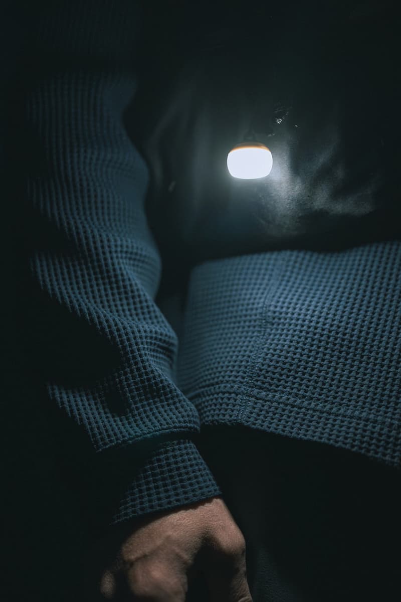 Snow Peak Micro Hozuki mini lantern clipped to a backpack strap, showing compact waterproof LED design