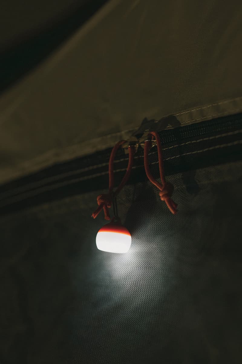 Snow Peak Micro Hozuki mini lantern clipped to a backpack strap, showing compact waterproof LED design