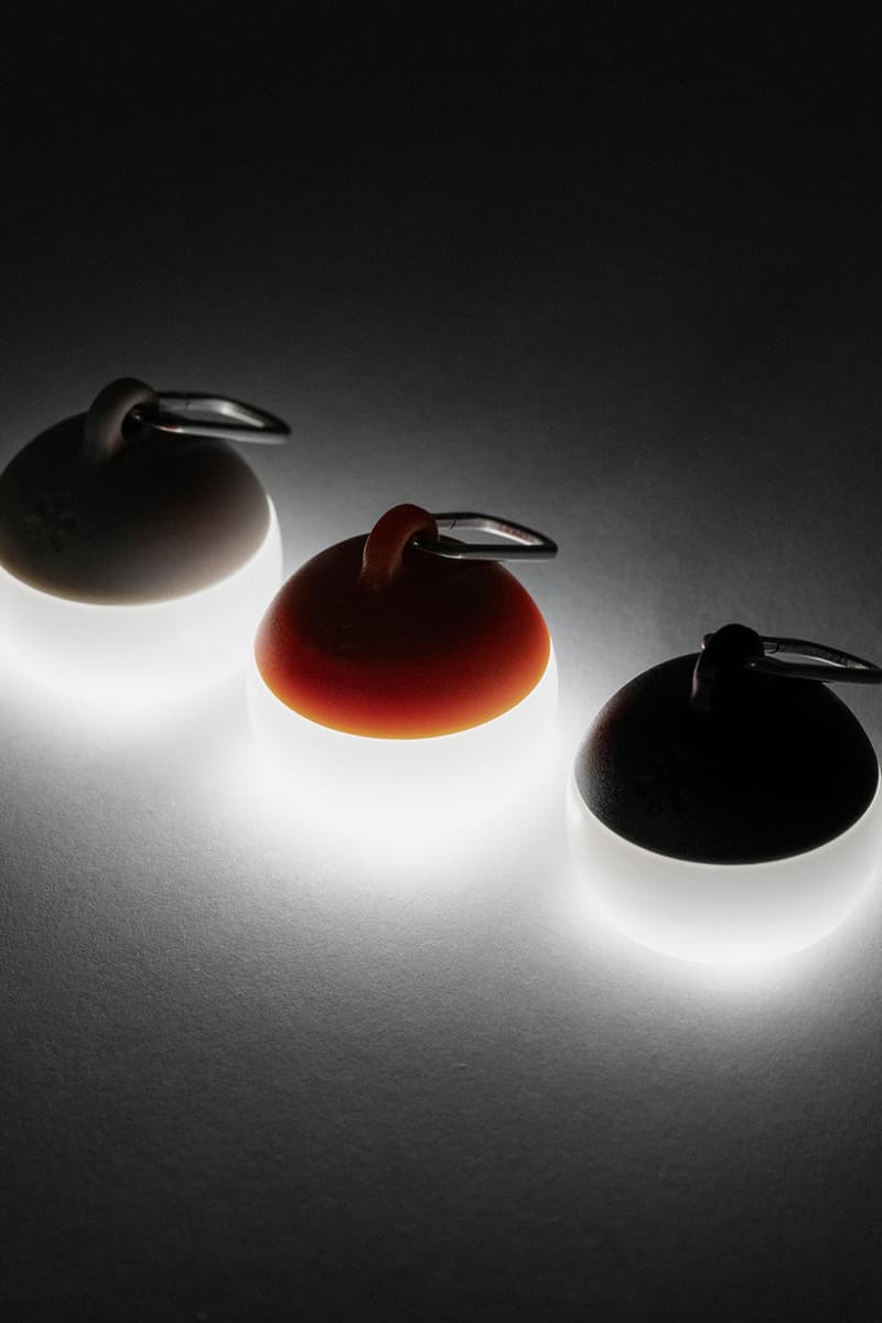 Snow Peak Micro Hozuki mini lantern clipped to a backpack strap, showing compact waterproof LED design