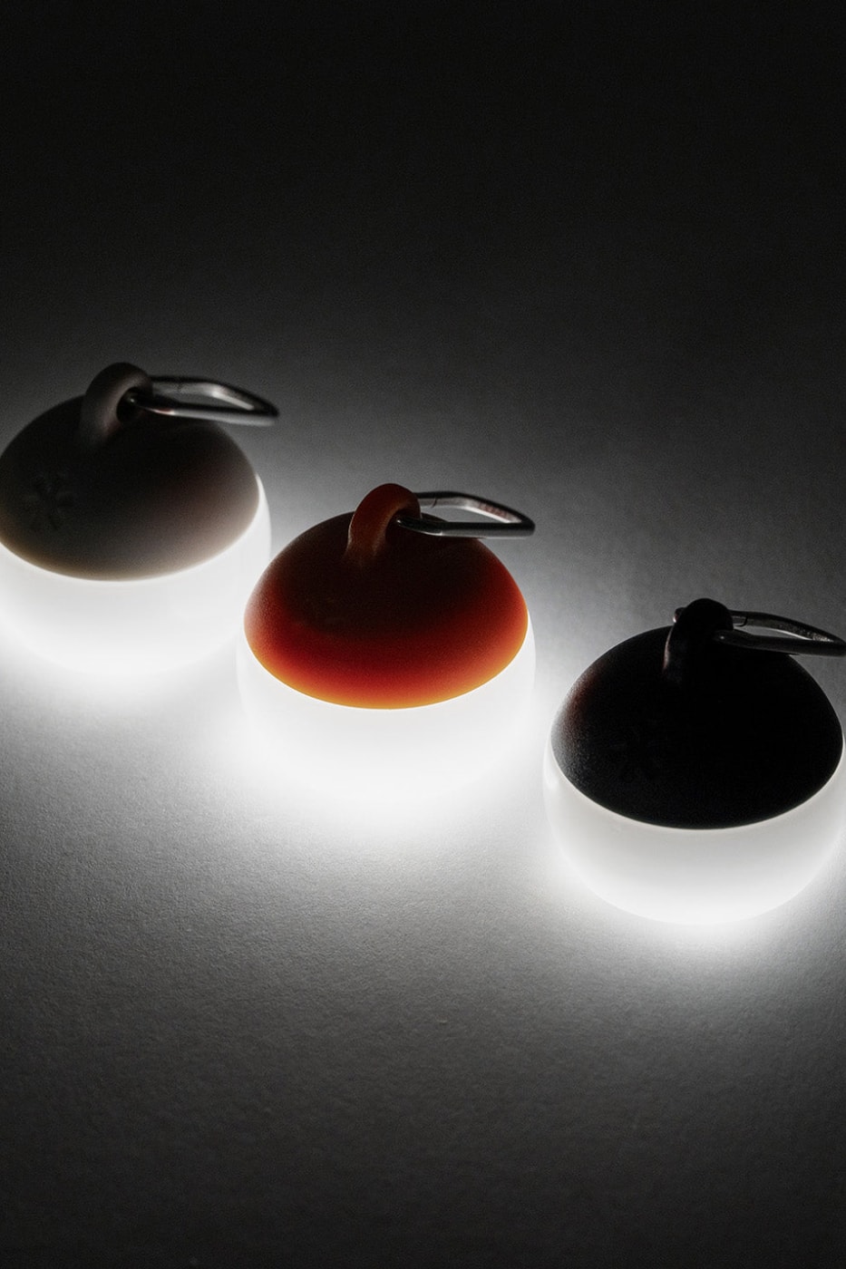 Snow Peak Micro Hozuki mini lantern clipped to a backpack strap, showing compact waterproof LED design