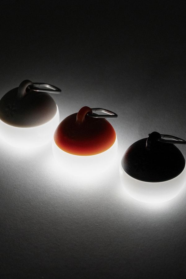 Snow Peak Micro Hozuki mini lantern clipped to a backpack strap, showing compact waterproof LED design