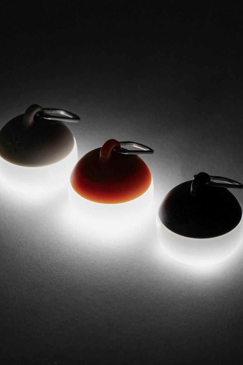 Snow Peak Micro Hozuki mini lantern clipped to a backpack strap, showing compact waterproof LED design