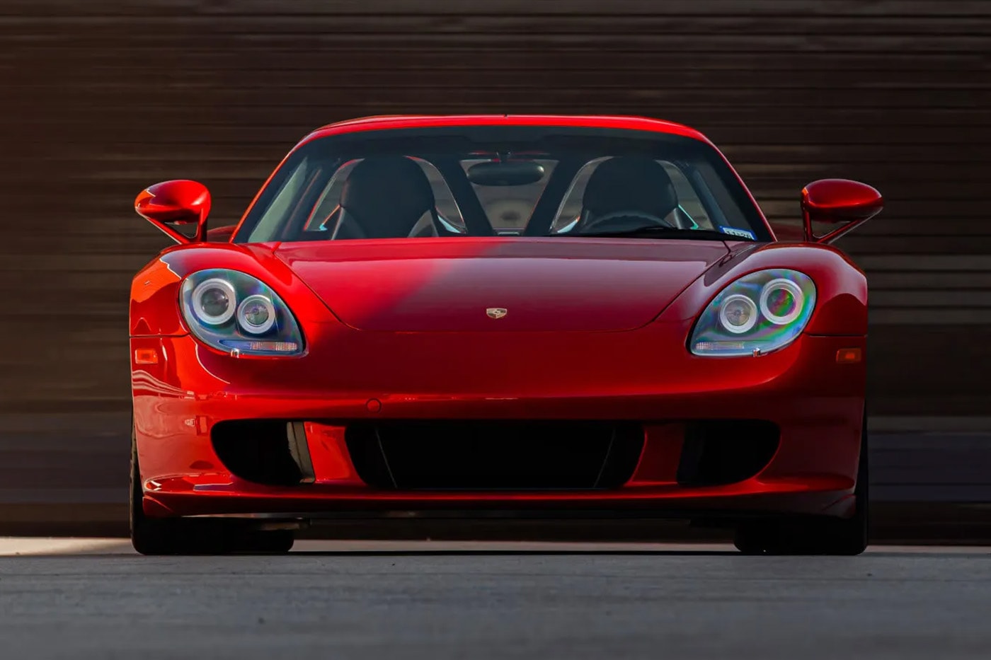 Porsche Carrera GT in Ferrari Rosso Fuoco at Mecum Monterey auction lot display