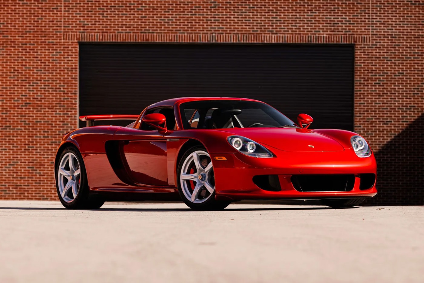 Porsche Carrera GT in Ferrari Rosso Fuoco at Mecum Monterey auction lot display