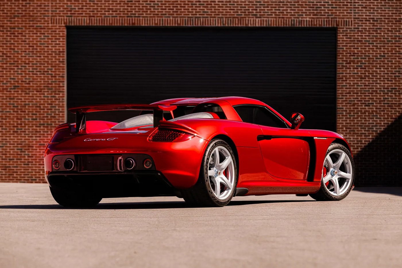 Porsche Carrera GT in Ferrari Rosso Fuoco at Mecum Monterey auction lot display