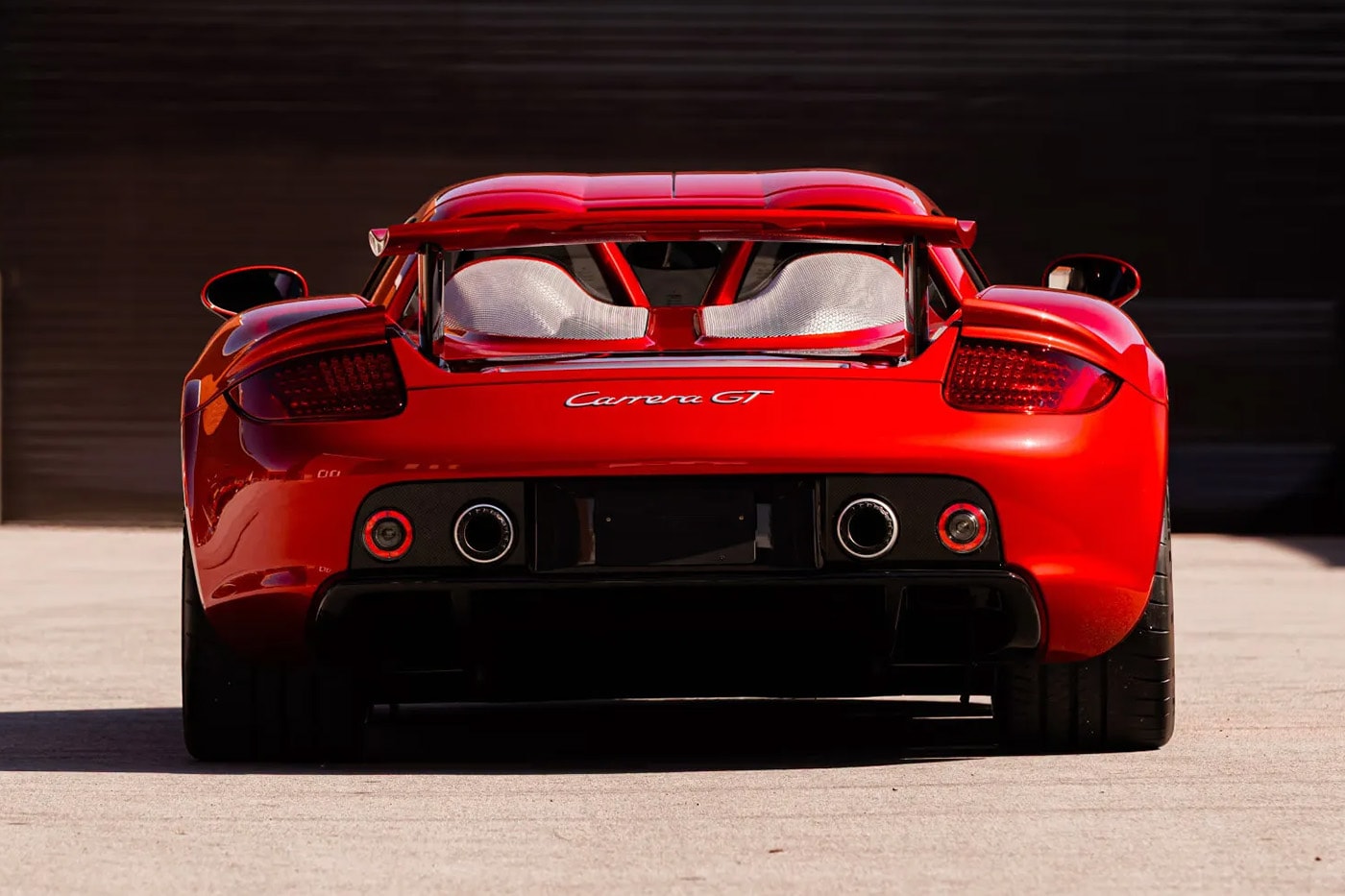 Porsche Carrera GT in Ferrari Rosso Fuoco at Mecum Monterey auction lot display