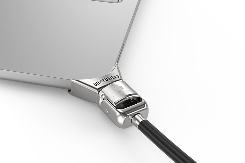 CompuLock Ledge lock adapter clamped to a MacBook Neo corner with cable lock attached