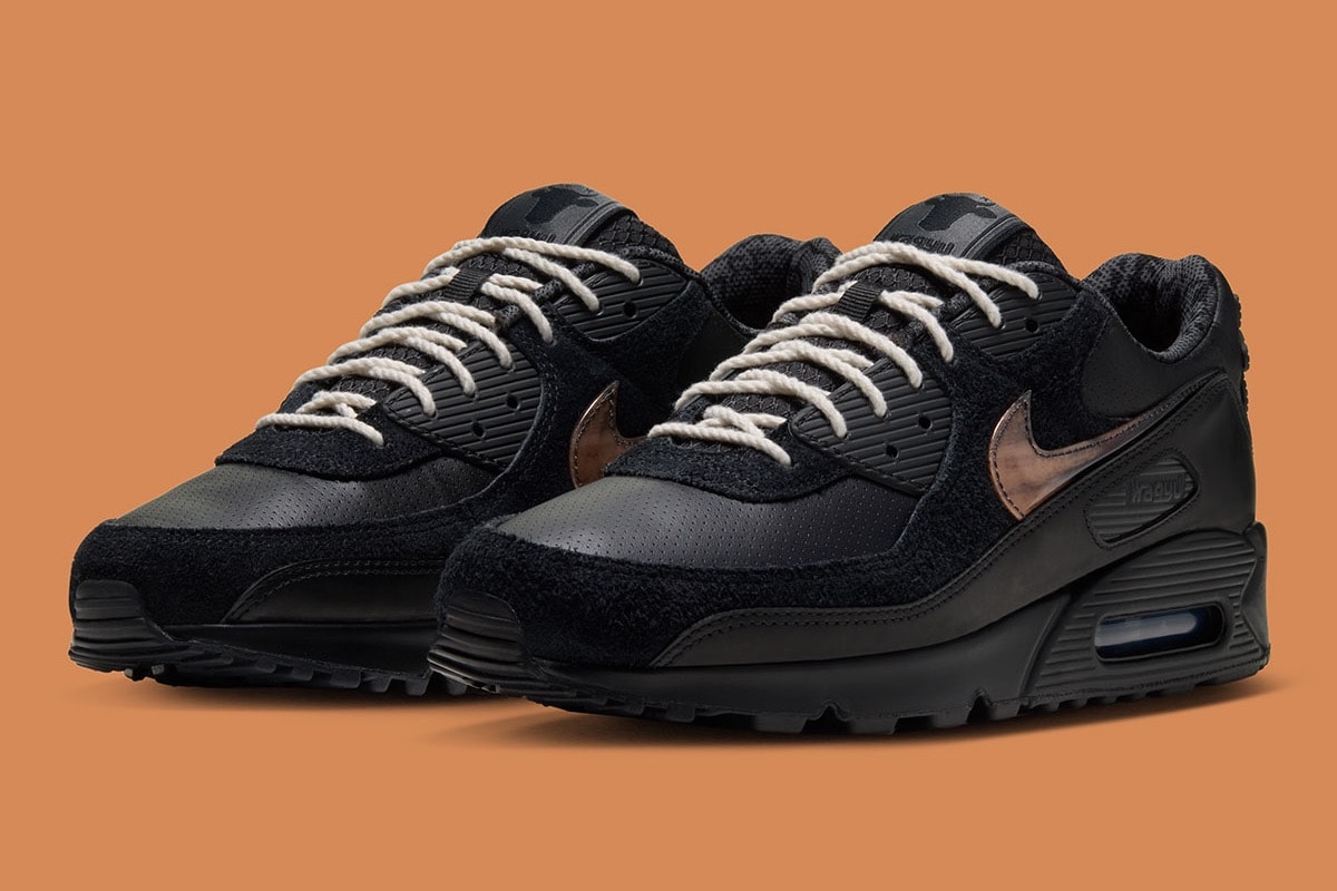 Pair of black Wagyu Nike Air Max 90 sneakers on an orange background