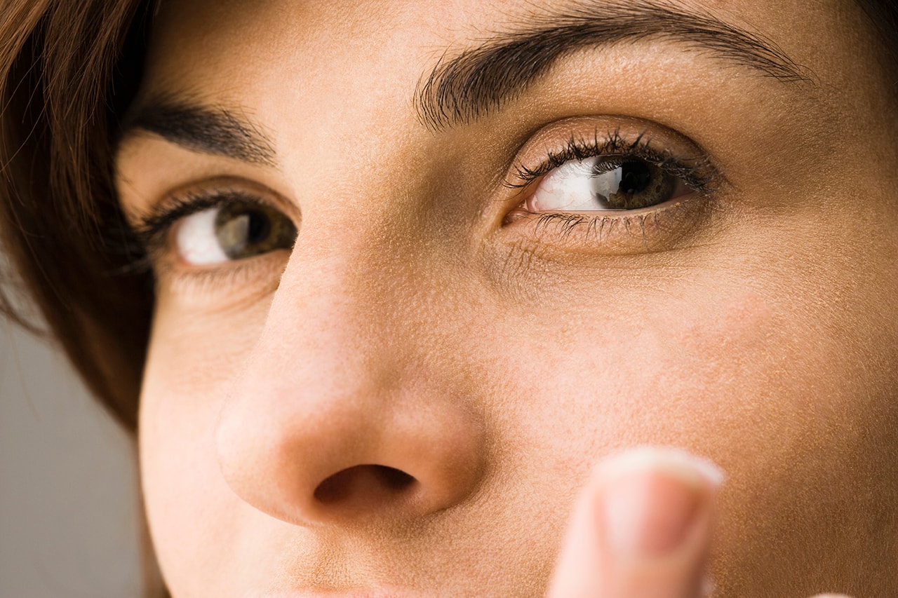 woman applying skincare concealer cream makeup eyes lashes brow