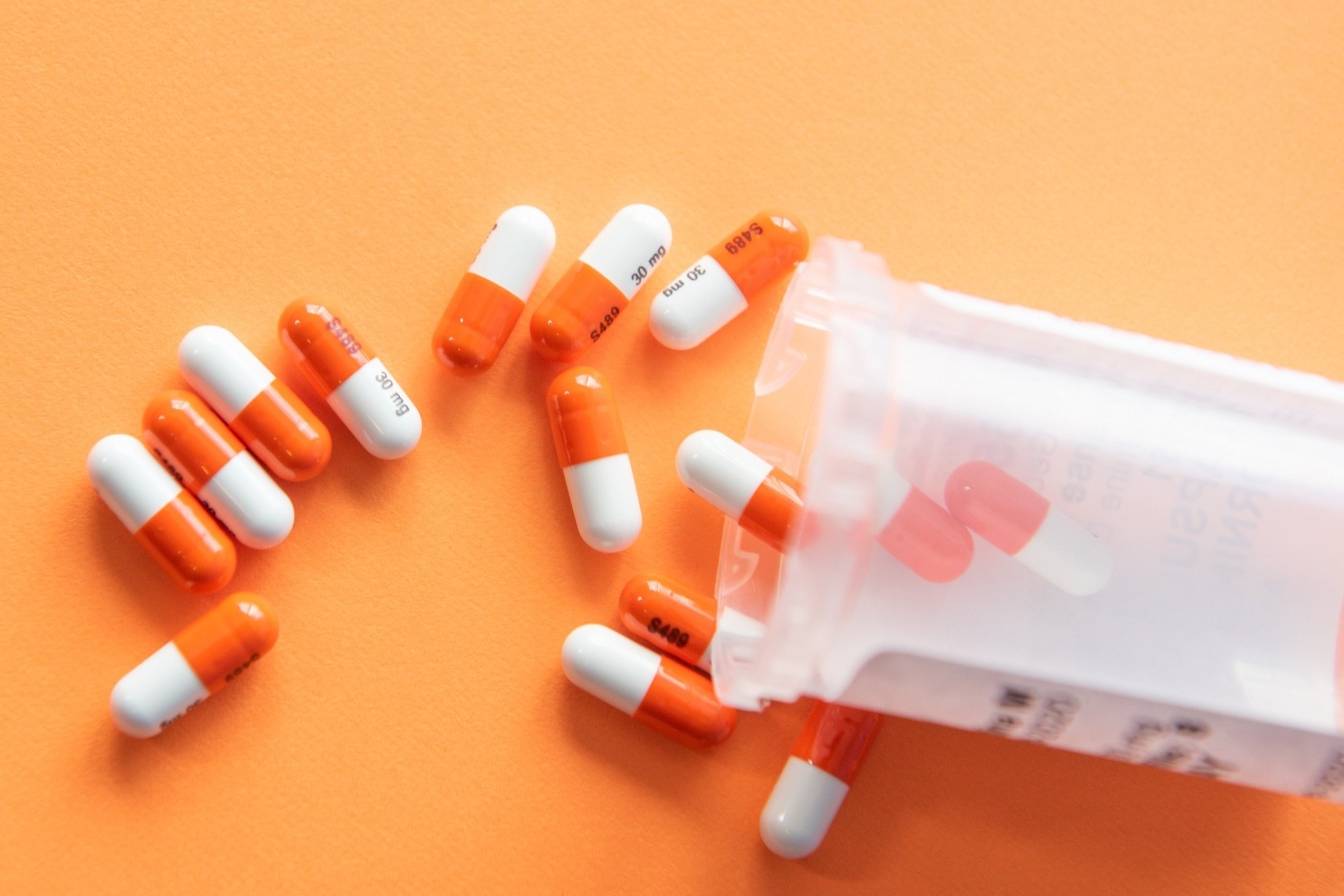 white orange pills pill bottle spilling orange backdrop health medicine