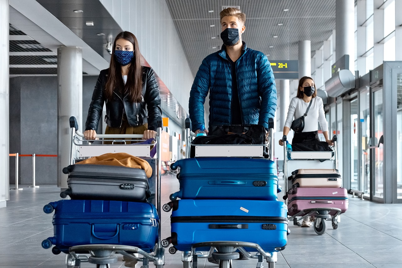people walking holding luggage airport covid-19 traveling face masks united states ban