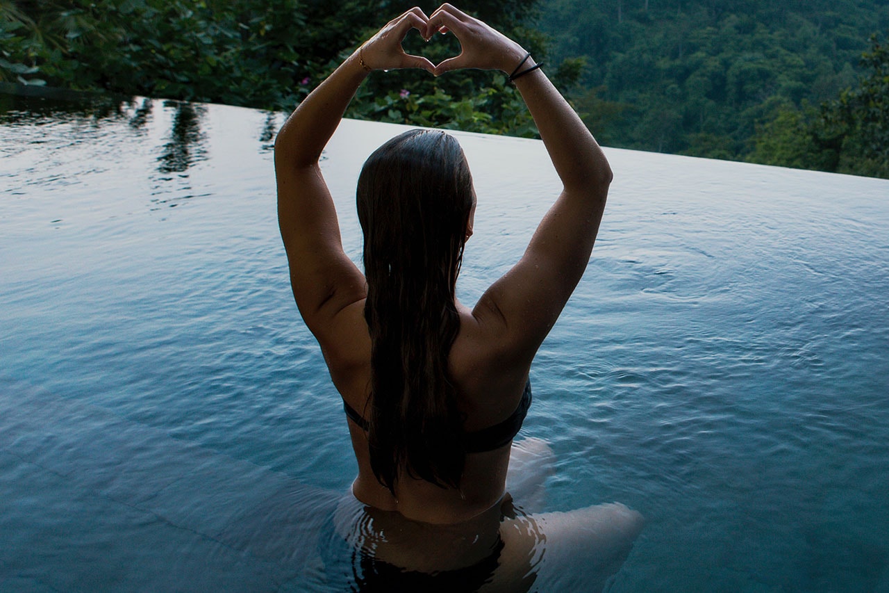 Woman Doing Yoga in Ocean Holding Up a Heart