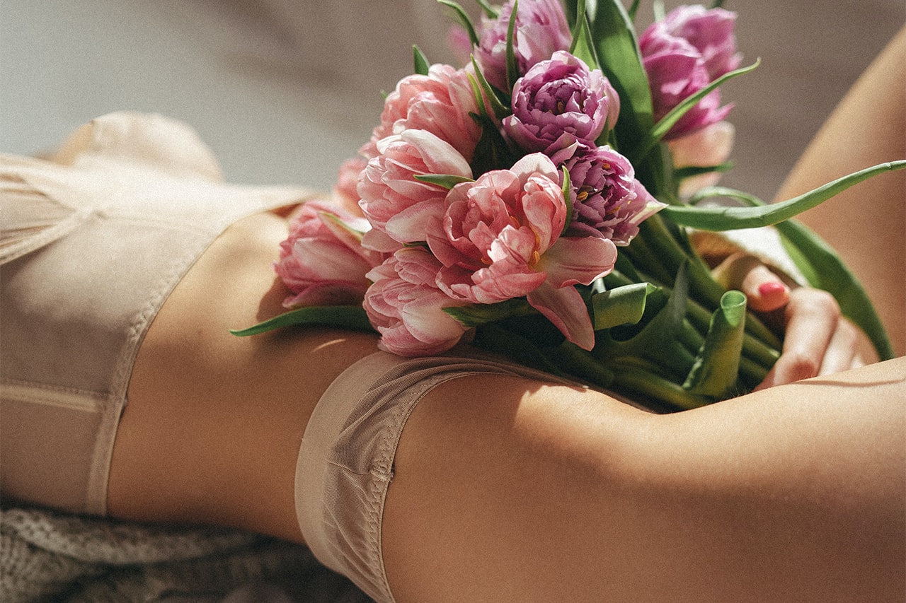 Boudoir Photoshoot of A Woman In Beige Lingerie Holding Bouquet of Flowers