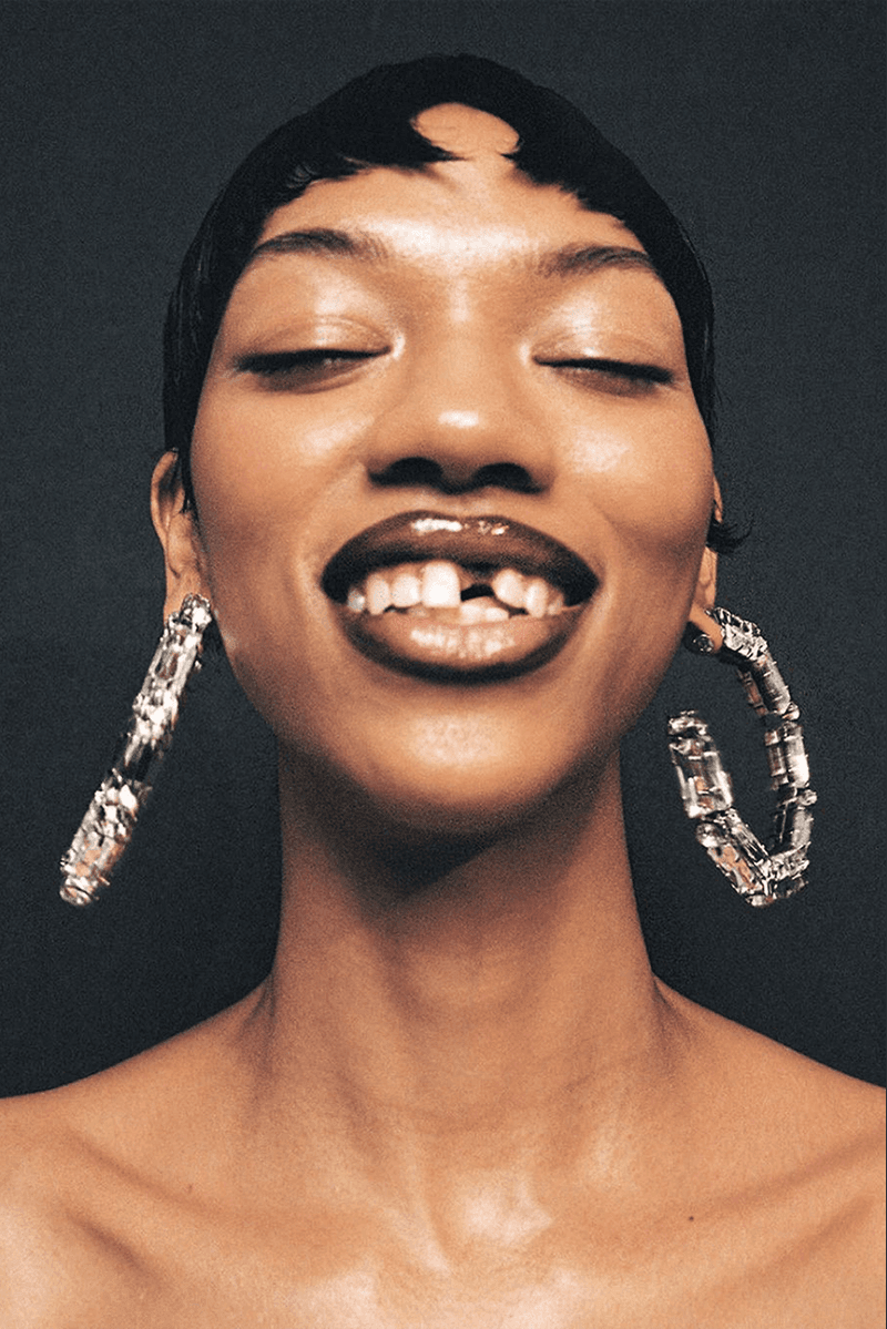 pressed powder, makeup, woman with gap in teeth and hoop earrings, short hair