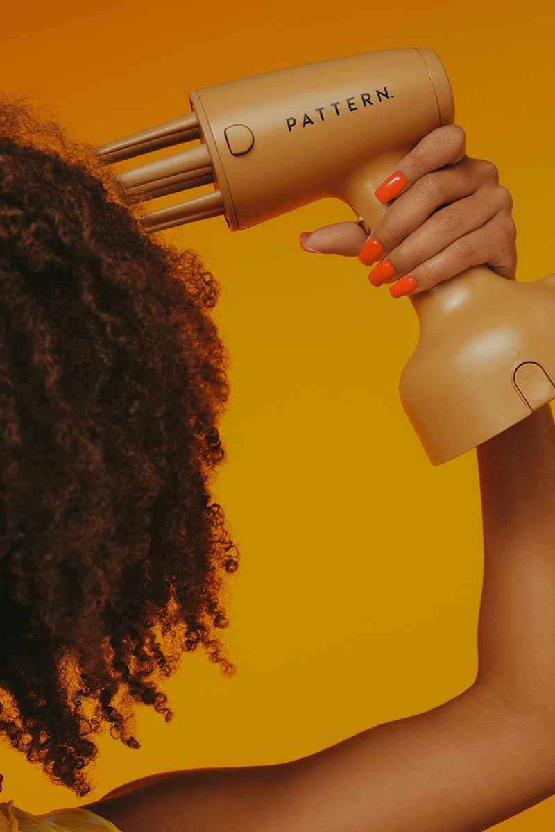 woman with bantu knots poses with pattern beauty haircare products, hair steamer, tracee ellis ross