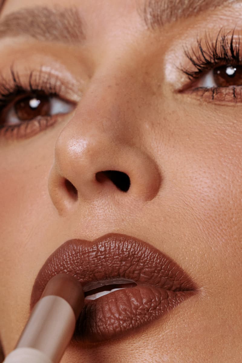 kim kardashian posing with red hair and new skkn by kim matte lipstick, makeup, skincare, kardashians