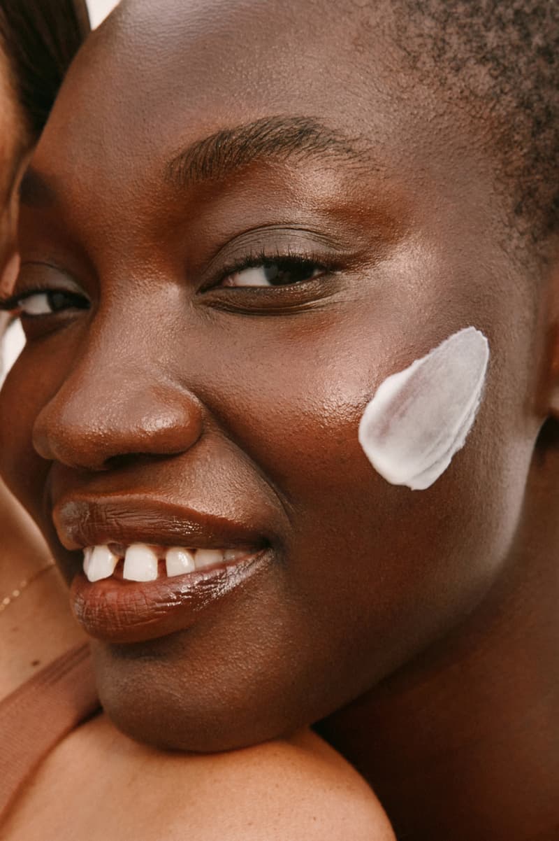 two women with moisturizer in between their faces, woman in a full ski outfit, ilia, halfdays ski suit, sportswear, snow apparel, beauty, skincare, barrier build skin protectant cream, moisturizer