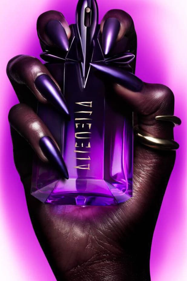 anok yai posing with a bottle of mugler alien extraintense, fragrance, perfume, beauty