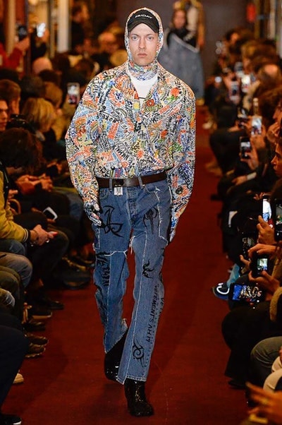 デムナワールドが炸裂した Vetements 2018年秋冬コレクション ストリート＆オーバーサイズという真骨頂の中でスカーフと壊滅的なミリタリーパンツを提案した圧巻のランウェイ パリファッションウィークの公式スケジュールから脱退した〈Vetements（ヴェトモン）〉が、レッドカーペットを敷き詰めた会場で宣言通りの単独ショーを開催した。ストリートとルーズシルエットというDemna Gvasalia（デムナ・ヴァザリア）の真骨頂の中で印象的に映るのは、スカーフの提案と壊滅的に近いミリタリーパンツのダメージ加工。落書きやワッペンの配置、多様多種な柄物のミックスからは、80年代〜90年代のヴィンテージ古着に見るカオティックな雰囲気が漂うほか、Marilyn Manson（マリリン・マンソン）のシャツなども組み込まれ、何とも形容し難いDemnaならではの世界観を構築して観衆を釘付けにした。 ちなみに、下のInstagramの動画はインビテーションであるレシートを撮影したもの。見応え満載の全57体のルックはフォトギャラリーからご確認を。 〈Vetements〉と〈Reebok（リーボック）〉によるブルーを効かせたGenetically Modified Pumpの限定カラーもお買い逃しのないように。
