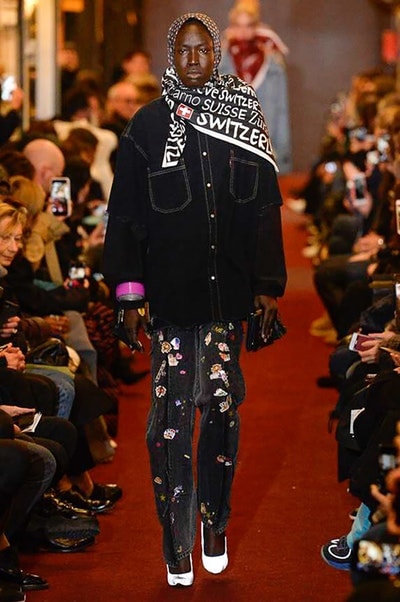デムナワールドが炸裂した Vetements 2018年秋冬コレクション ストリート＆オーバーサイズという真骨頂の中でスカーフと壊滅的なミリタリーパンツを提案した圧巻のランウェイ パリファッションウィークの公式スケジュールから脱退した〈Vetements（ヴェトモン）〉が、レッドカーペットを敷き詰めた会場で宣言通りの単独ショーを開催した。ストリートとルーズシルエットというDemna Gvasalia（デムナ・ヴァザリア）の真骨頂の中で印象的に映るのは、スカーフの提案と壊滅的に近いミリタリーパンツのダメージ加工。落書きやワッペンの配置、多様多種な柄物のミックスからは、80年代〜90年代のヴィンテージ古着に見るカオティックな雰囲気が漂うほか、Marilyn Manson（マリリン・マンソン）のシャツなども組み込まれ、何とも形容し難いDemnaならではの世界観を構築して観衆を釘付けにした。 ちなみに、下のInstagramの動画はインビテーションであるレシートを撮影したもの。見応え満載の全57体のルックはフォトギャラリーからご確認を。 〈Vetements〉と〈Reebok（リーボック）〉によるブルーを効かせたGenetically Modified Pumpの限定カラーもお買い逃しのないように。