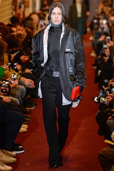 デムナワールドが炸裂した Vetements 2018年秋冬コレクション ストリート＆オーバーサイズという真骨頂の中でスカーフと壊滅的なミリタリーパンツを提案した圧巻のランウェイ パリファッションウィークの公式スケジュールから脱退した〈Vetements（ヴェトモン）〉が、レッドカーペットを敷き詰めた会場で宣言通りの単独ショーを開催した。ストリートとルーズシルエットというDemna Gvasalia（デムナ・ヴァザリア）の真骨頂の中で印象的に映るのは、スカーフの提案と壊滅的に近いミリタリーパンツのダメージ加工。落書きやワッペンの配置、多様多種な柄物のミックスからは、80年代〜90年代のヴィンテージ古着に見るカオティックな雰囲気が漂うほか、Marilyn Manson（マリリン・マンソン）のシャツなども組み込まれ、何とも形容し難いDemnaならではの世界観を構築して観衆を釘付けにした。 ちなみに、下のInstagramの動画はインビテーションであるレシートを撮影したもの。見応え満載の全57体のルックはフォトギャラリーからご確認を。 〈Vetements〉と〈Reebok（リーボック）〉によるブルーを効かせたGenetically Modified Pumpの限定カラーもお買い逃しのないように。